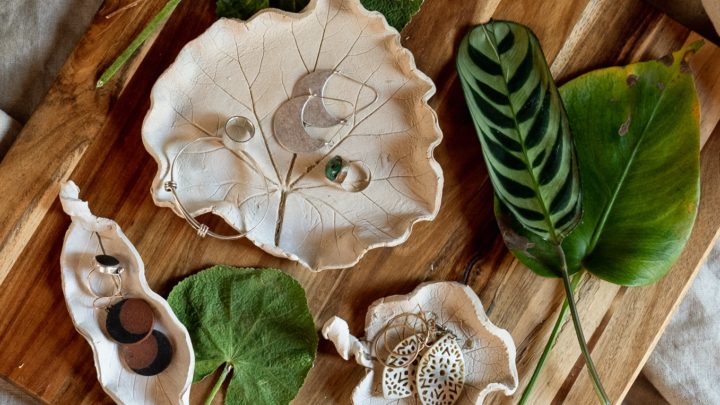 A leaf shaped trinket dish containing small pieces of jewelry