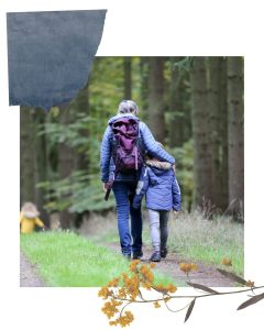 An adult and child walking away into the woods
