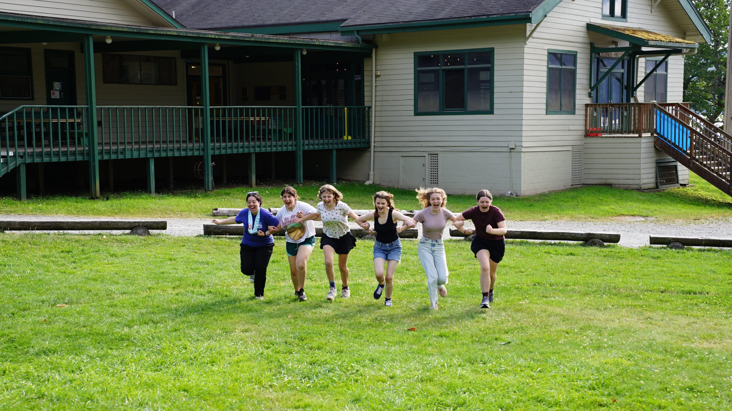 a group of campers and their counselor run through the orchard happily