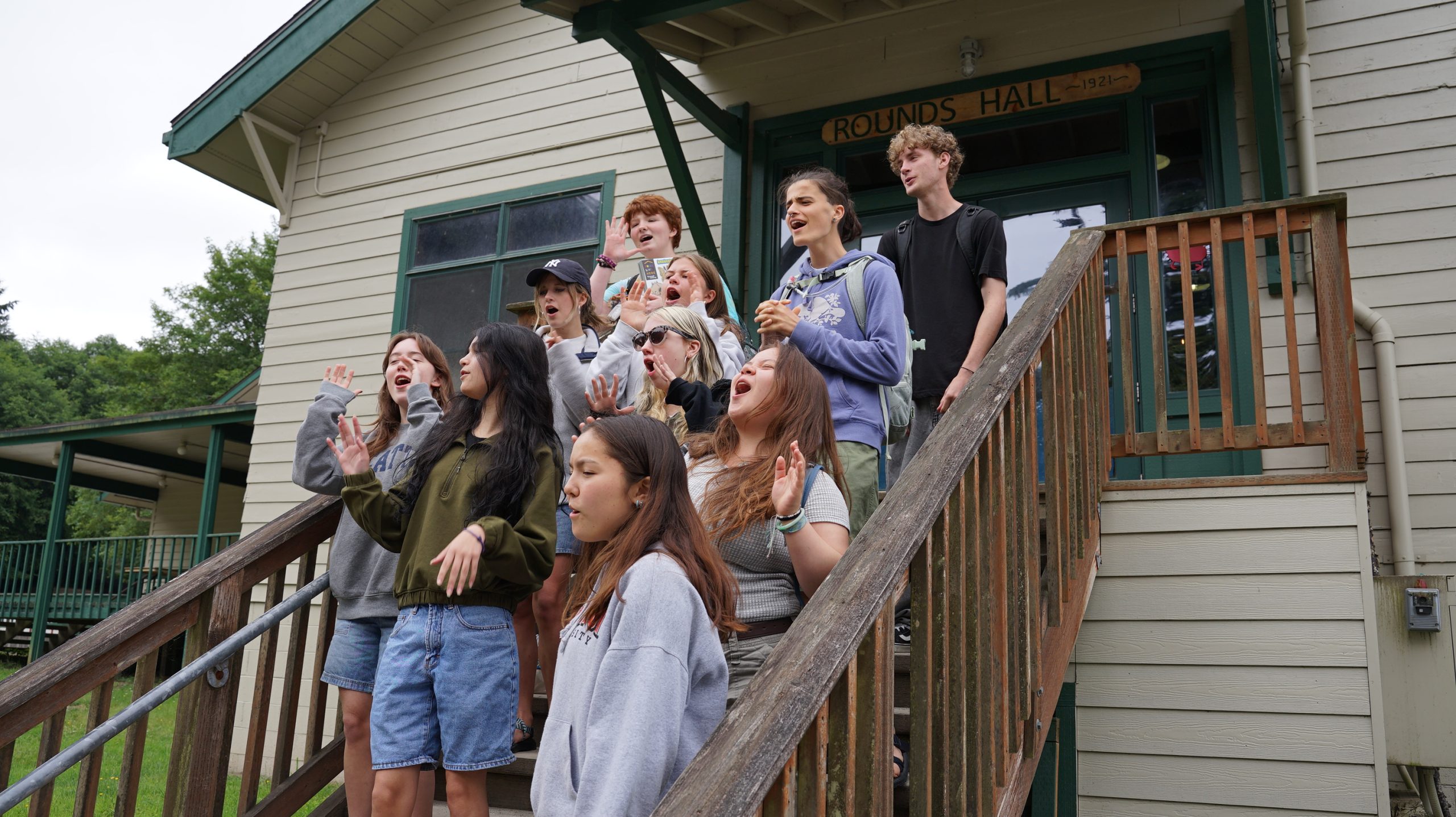 Teen leaders singing on the porch of rounds hall before a meal