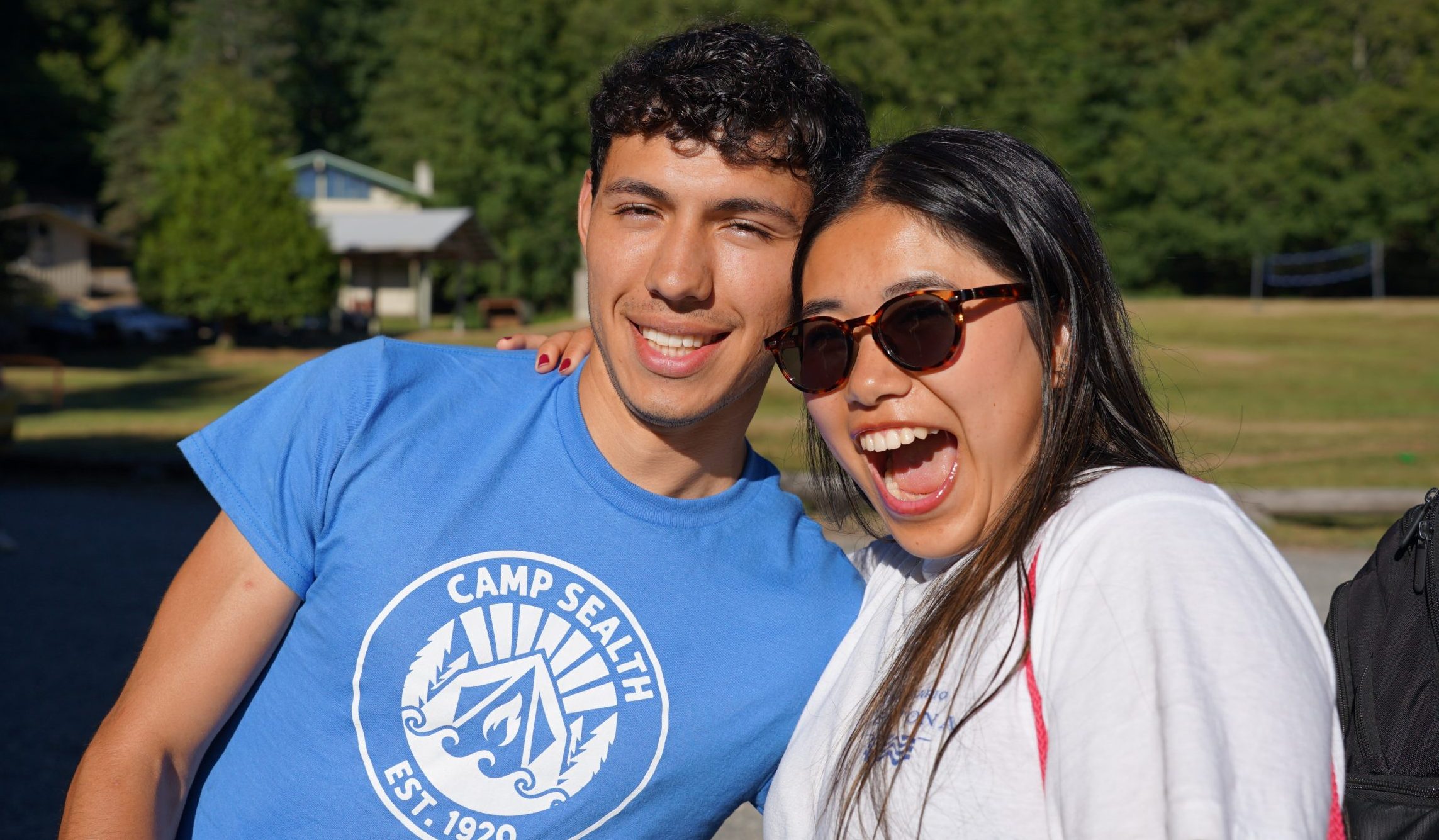 two international staff flash smiles while posing at camp sealth