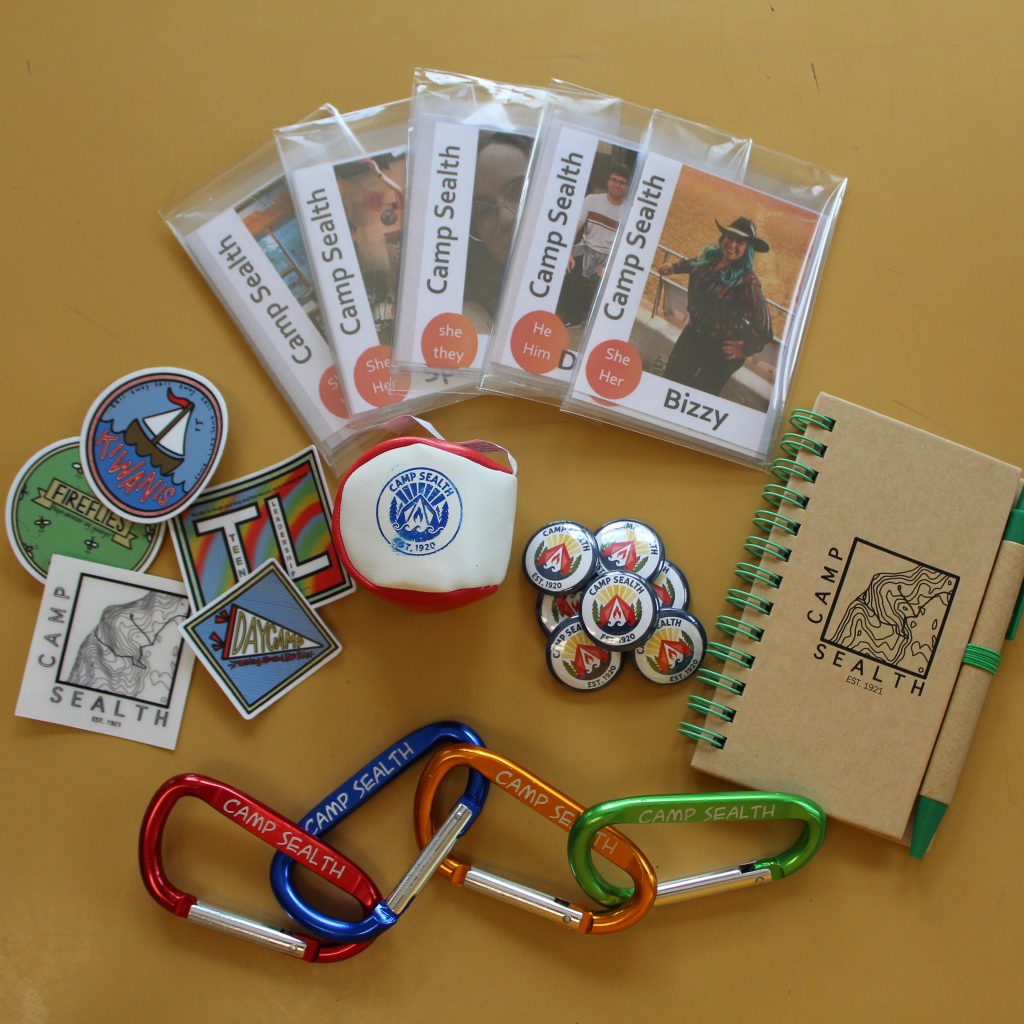 Small items in the camp store like caribeeners, patches, buttons with the Camp Sealth logo, and trading cards featuring staff photos