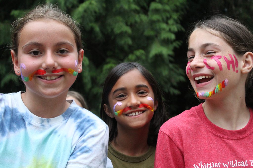 three smiling campers with face paint on