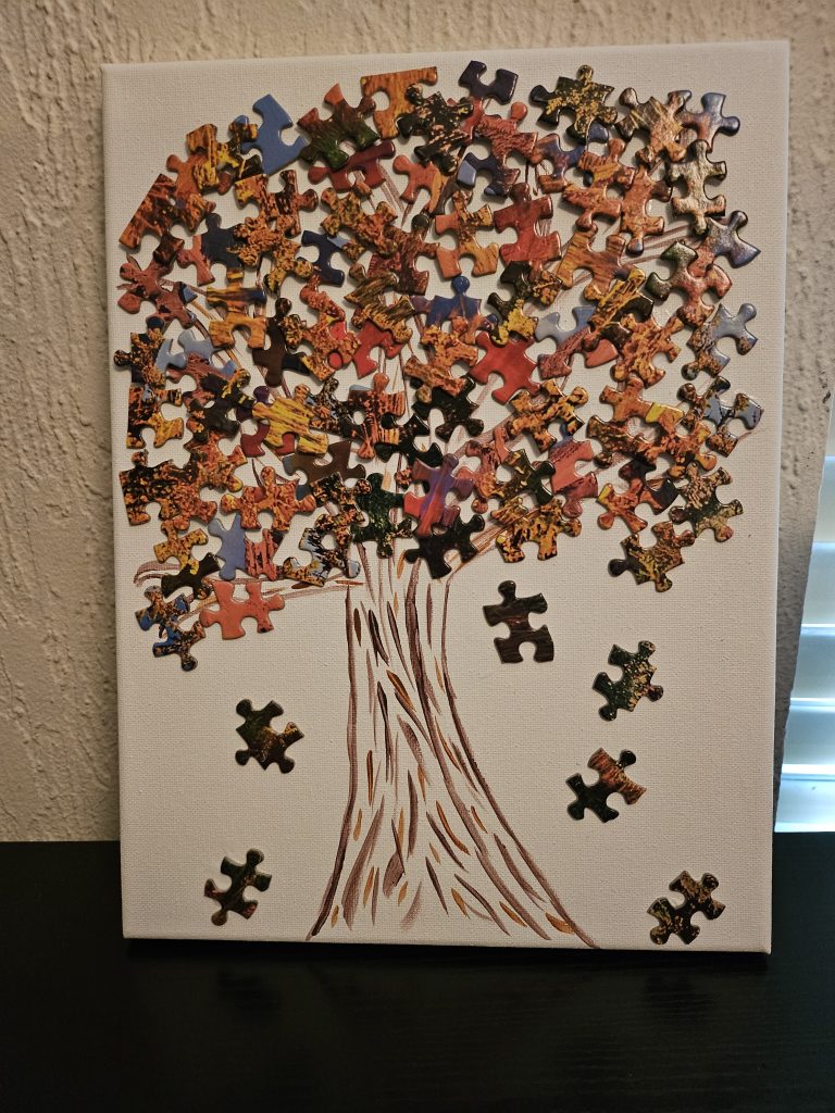 A tree painting using jigsaw puzzle pieces as the leaves.