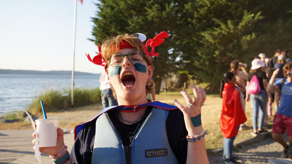 a camper dressed in life jacket and funny hat with painted face roars