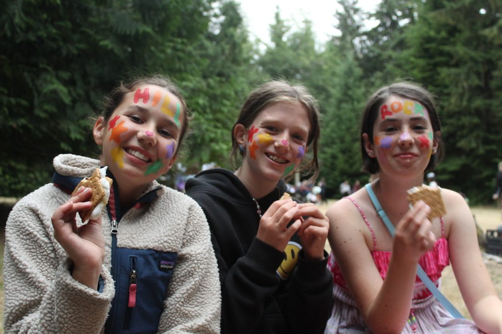 3 kids with painted faces eating smores