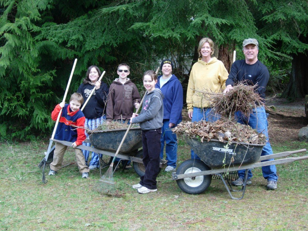 Seven people of various ages pose with gardening tools.